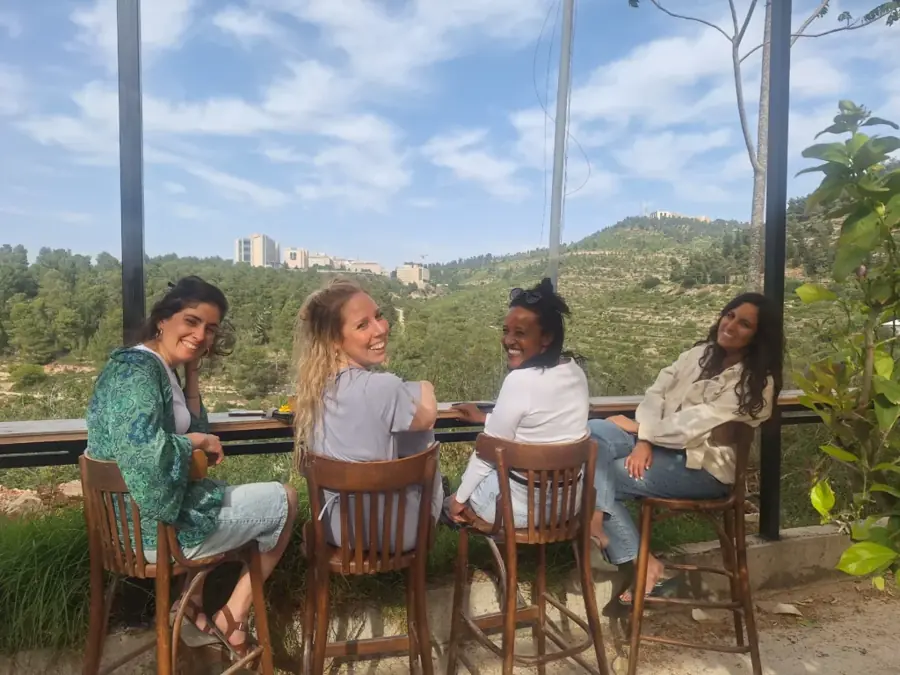 חברות יושבות עם בירה של פפא מול נוף הרי ירושלים
